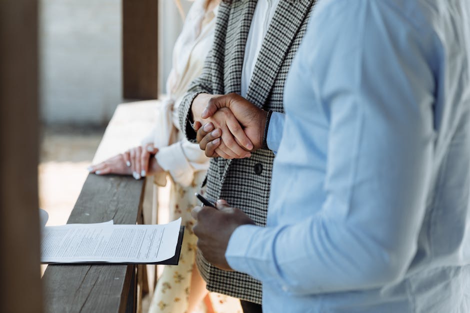 A real estate agent and seller shaking hands over a signed contract to sell house